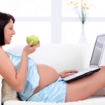 Pregnant young woman using a laptop computer on home.